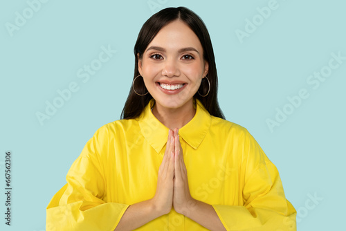 Happy young woman holding hand in namaste gesture