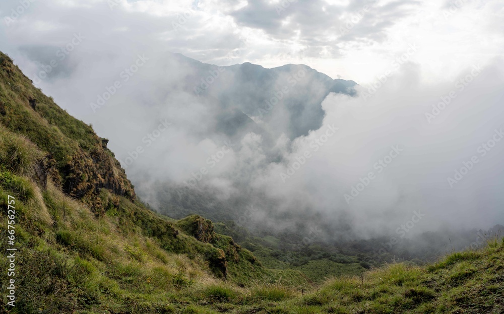 a steep slope with a fog covering the mountains below it
