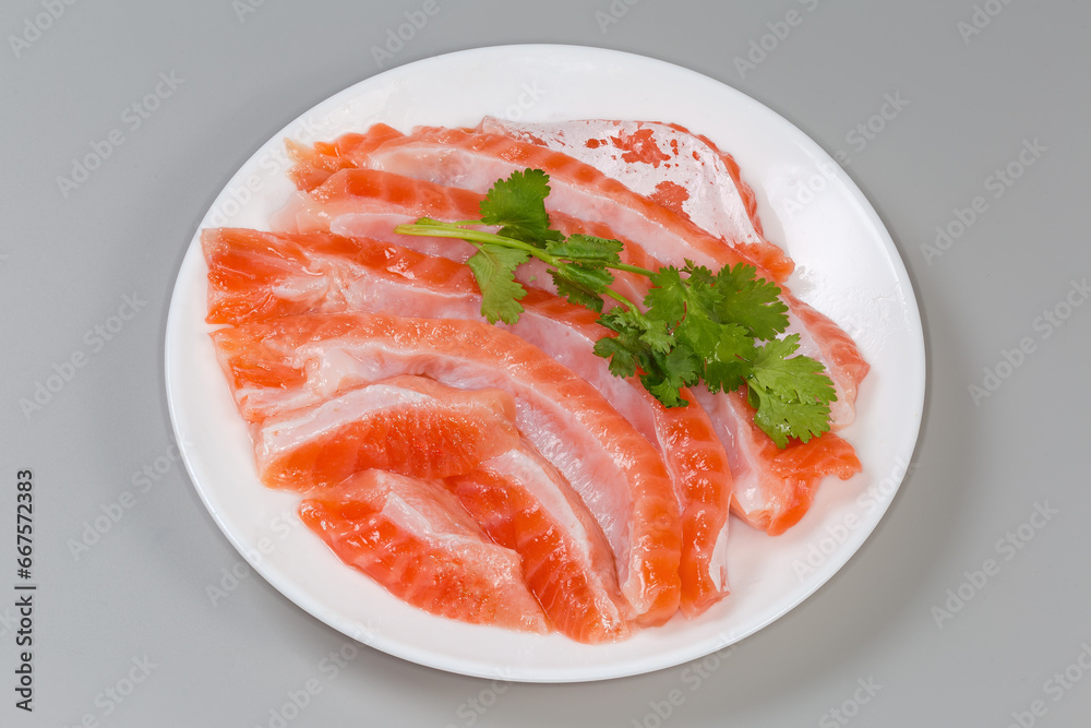 Salted slices of salmon bellies with cilantro twigs on dish Salted slices of salmon bellies with cilantro twigs on dish