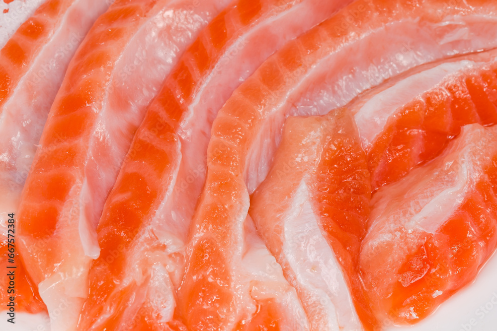 Salted salmon bellies strips on dish, fragment close-up Salted salmon bellies strips on dish, fragment close-up