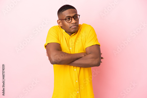 Young latin man isolated on pink background making doubts gesture while lifting the shoulders