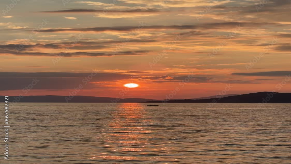 Dramatic sunset against the sea. Sky painted red and orange, clouds in purple Dramatic sunset against the sea. Sky painted red and orange, clouds in purple