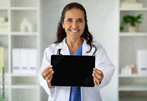 Happy woman therapist holding digital tablet with empty screen © Prostock-studio