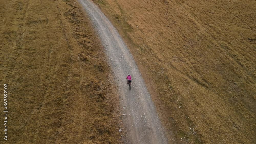 Aerial view of a woman cyclist cycling outdoors.Cyclist riding a gravel bike.Gravel biking concept.Cycling and healthy lifestyle.Woman cyclist wearing cycling uniform and helmet.Offroad bike adventure Aerial view of a woman cyclist cycling outdoors.Cyclist riding a gravel bike.Gravel biking concept.Cycling and healthy lifestyle.Woman cyclist wearing cycling uniform and helmet.Offroad bike adventure