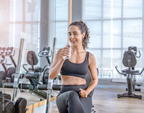 Exhausted woman in sportswear sitting at fitness training in .sporty athletic woman warm up training sitting near treadmill look aside in gym indoor Workout sport motivation