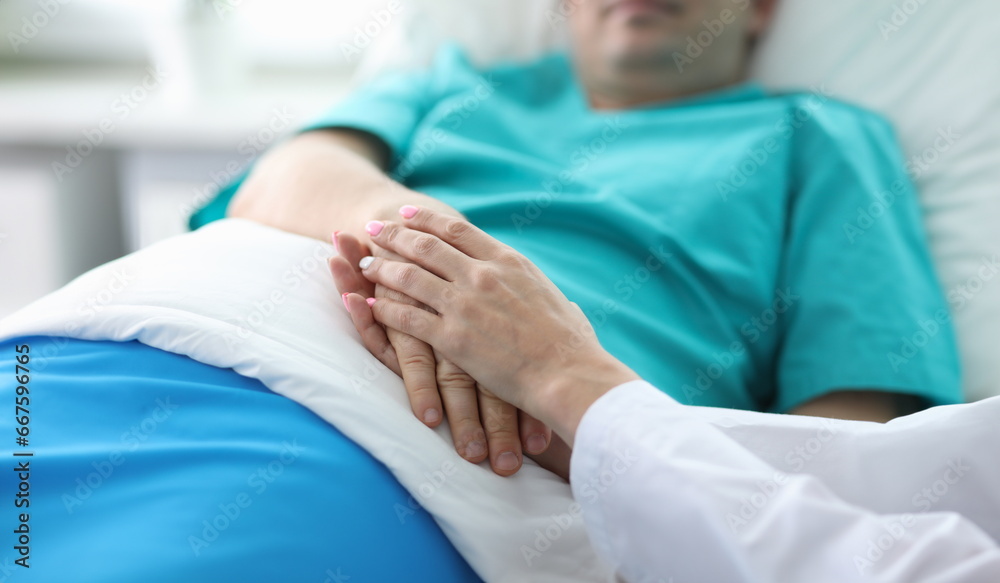 Doctors hands hold hands patient lying in ward. Treatment and prevention many diseases. Manifestations human attention to patients in serious condition. Highly qualified professional medical staff Doctors hands hold hands patient lying in ward. Treatment and prevention many diseases. Manifestations human attention to patients in serious condition. Highly qualified professional medical staff