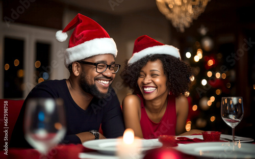 Young African American couple wearing Santa hats laughing and enjoying Christmas dinner in their cozy home with lights bokeh in the background. Christmas and New Year festivities concept