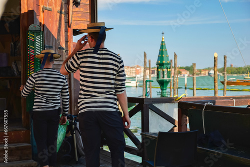 Fotografi Two gondoliers at the pier of the Venetian Lagoon in Venice, Italy