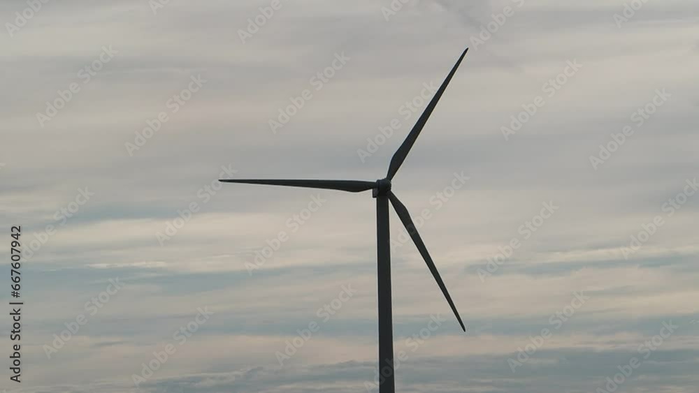 Wind turbines at dawn blue sky with clouds Wind farm generating green energy.Wind turbine blades rotate against a blue sky on a sunny day. Energy production with renewable energy. 