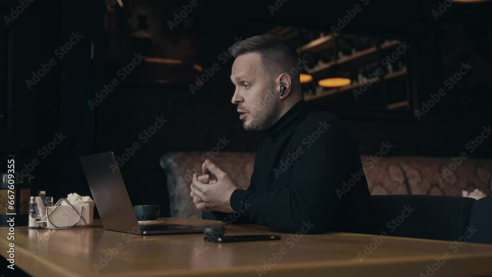 Portrait of an elegant man in a cafe with a laptop. A manager holds a video conference with colleagues or friends. Communication via video call.