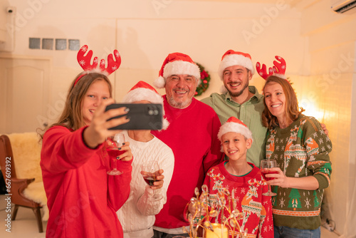 Merry Christmas and Happy Holidays, Cheerful grandparents grandchildren sister brother, son daughter taking self photo, photographing on mobile cell cellphone phone.