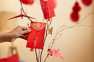 Minimal closeup of female hand holding hongbao red envelope as Chinese New Year tradition, copy space Have overflowing abundance every year