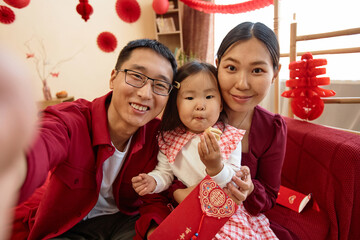 POV of happy Asian family wearing red on Chinese new year and taking selfie photo together at home Have overflowing abundance every year