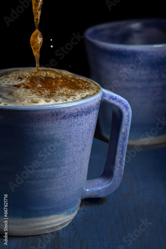 Close up of blue porcelain coffee cups with froth on a black background