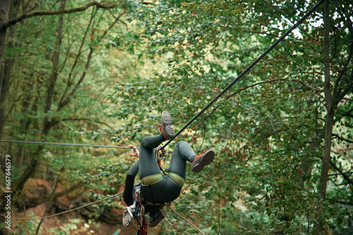 Climbing in the forest. Woman is in the forest using the safety equipment