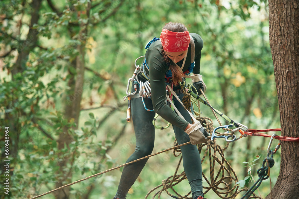 Woman is doing climbing in the forest by the use of safety equipment