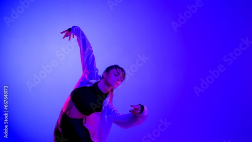 Young woman wearing a top, shorts and a shirt performing contemporary dance in studio. Neon blue, pink and red color scheme, ombre, gradient background. Medium sized.
