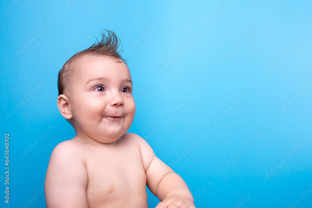 A nine-month-old baby on a blue background. Looks, emotional, funny, copy space. A nine-month-old baby on a blue background. Looks, emotional, funny, copy space.