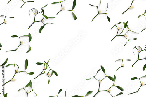 Branches with leaves and white berries of mistletoe on a white background with space for text. Top view, flat lay