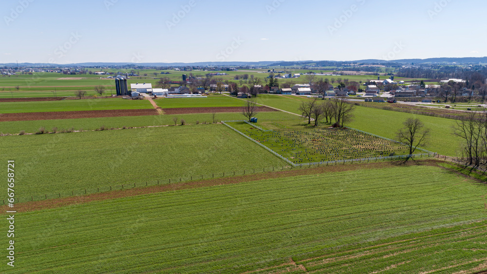 An Aerial View of Pennsylvania Dutch Farmlands with an Amish Cemetery in it on a Sunny Spring Day