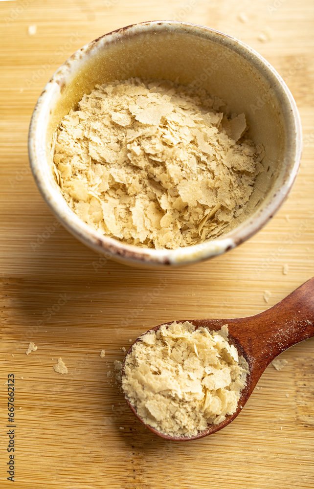 Close-up of a bowl and a wooden spoon with nutritional yeast, excellent vegan protein Close-up of a bowl and a wooden spoon with nutritional yeast, excellent vegan protein