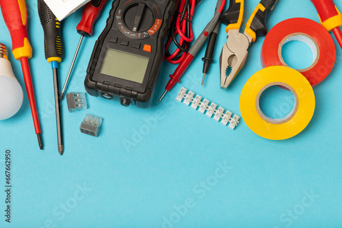 Electrician tools on background. Multimeter,construction tape,electrical tape, screwdrivers,pliers,an automatic insulation stripper, socket and LED lamp. Flatley. electrician concept. photo