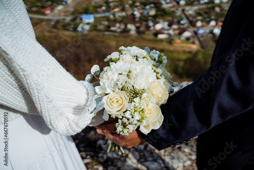 Newlyweds holding a wedding bouquet in their hands, flowers at the wedding shot close-up, a holiday for two, a solemn event.