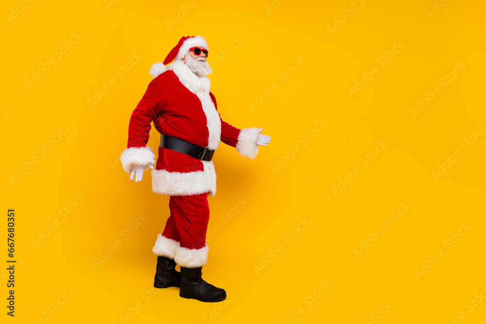 Full size profile photo of santa claus walk empty space christmas miracle isolated on yellow color background Full size profile photo of santa claus walk empty space christmas miracle isolated on yellow color background