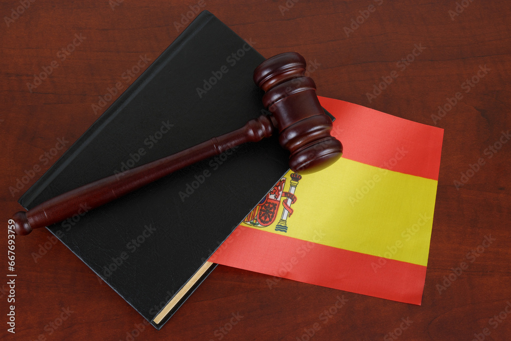 Judge gavel on legal book and flag of Spain.
