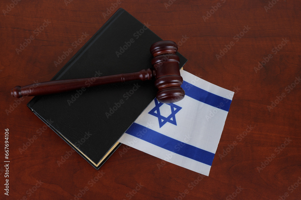 Wooden judge gavel and legal book with flag of Israel on table. 