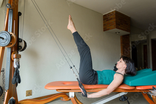 adult woman at home training her body with pulley and weight exercise machine