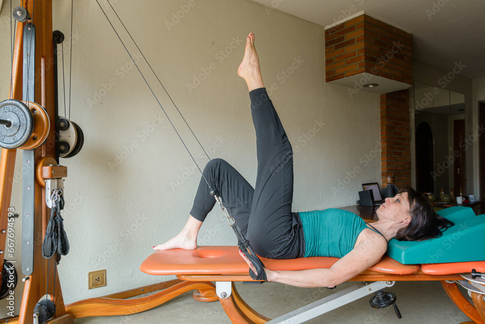 adult woman at home training her body with pulley and weight exercise machine