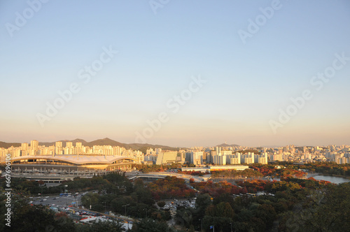 SEOUL, SOUTH KOREA - OCTOBER 24, 2022: Colourful foliage trees in Autumn with various buildings in the afternoon and blue sky.