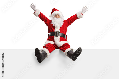 Bild auf Leinwand Full length portrait of an excited santa claus sitting on a blank panel