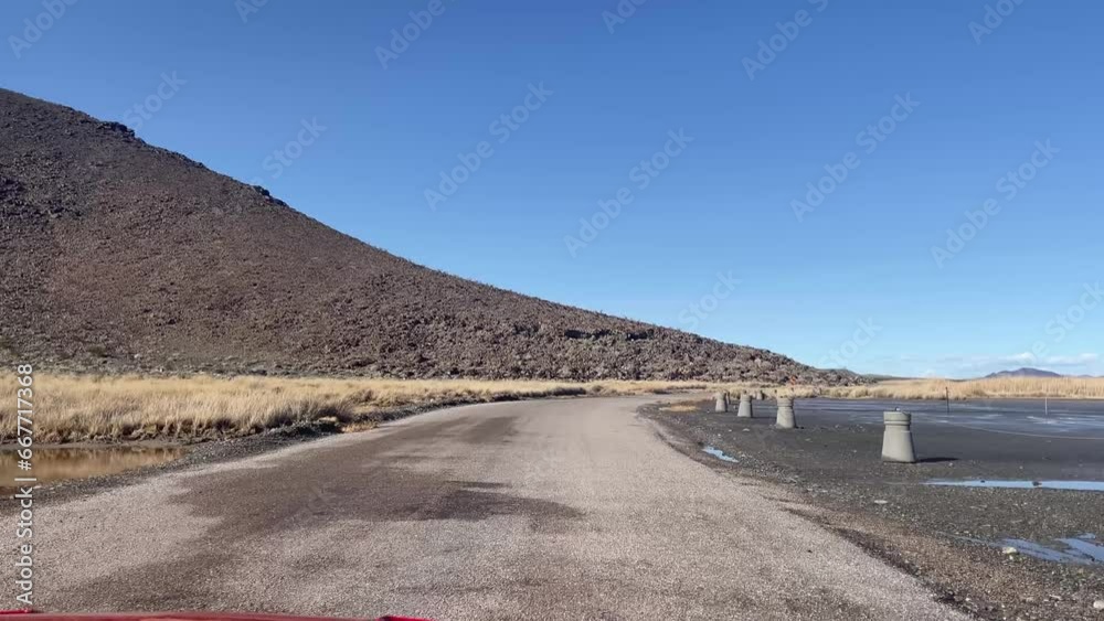 Driving on a highway through the Mojave Desert, heading towards Las Vegas in Nevada with a blue sky and a hot day.