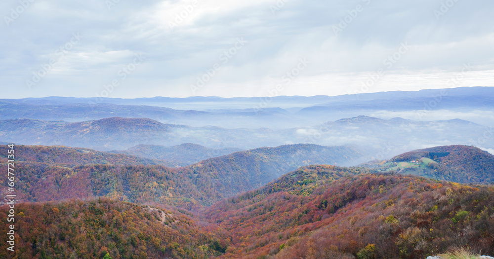Panoramic mountain autumn landscape with beautiful cloudy sky and lush wilderness.