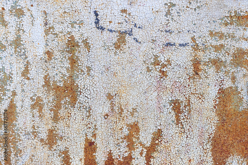 The texture of a cracked layer of paint on a metal sheet with rust showing through.