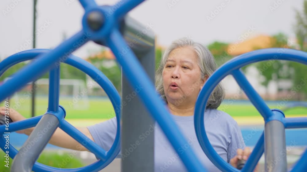 Senior Asian woman in casual workout in exercise stations in public park. Represents keeping young with physical activity, Open air gym. Physical health concept. Outdoor fitness equipment in city park Senior Asian woman in casual workout in exercise stations in public park. Represents keeping young with physical activity, Open air gym. Physical health concept. Outdoor fitness equipment in city park