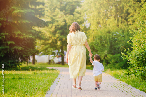 Billede på lærred A child takes steps holding a mother woman by the hand along a path in nature