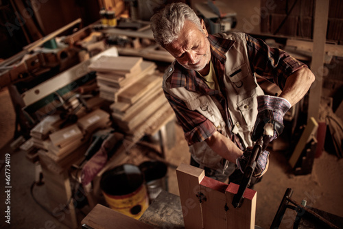 Elderly experienced carpenter choosing wood for the job