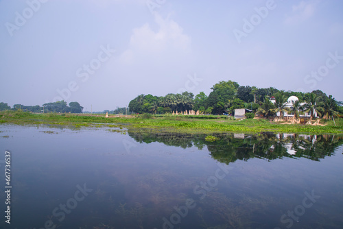 Reflection of trees in the lake water against the blue sky landscape countryside in Bangladesh
