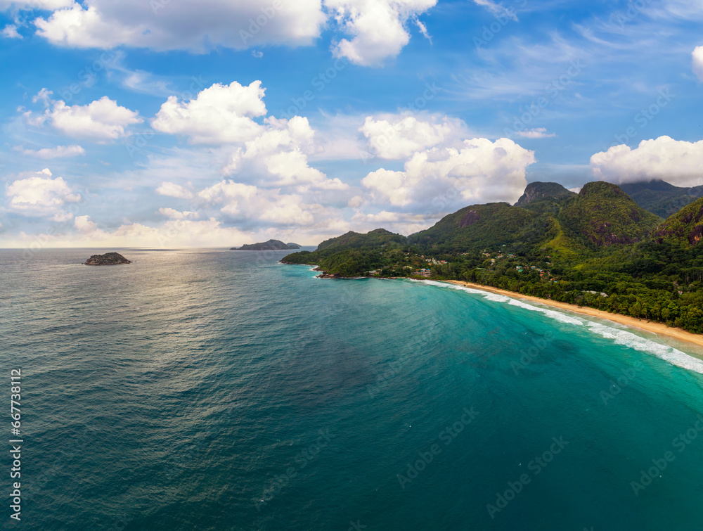 Aerial view of Grand Anse Beach at the Mahe Island, Seychelles, with turquoise water of the Indian Ocean, mountains and rain forests.