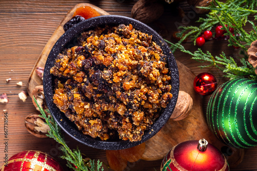 Homemade Christmas sweet mincemeat bowl, dried fruit mince meat for traditional winter mince pies with cinnamon sticks, anise, with festive decorations and christmas tree branches