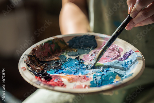 artist brush mix color painting on palette is holding in his hand closeup