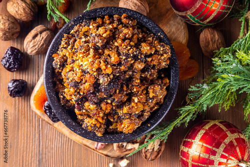 Homemade Christmas sweet mincemeat bowl, dried fruit mince meat for traditional winter mince pies with cinnamon sticks, anise, with festive decorations and christmas tree branches