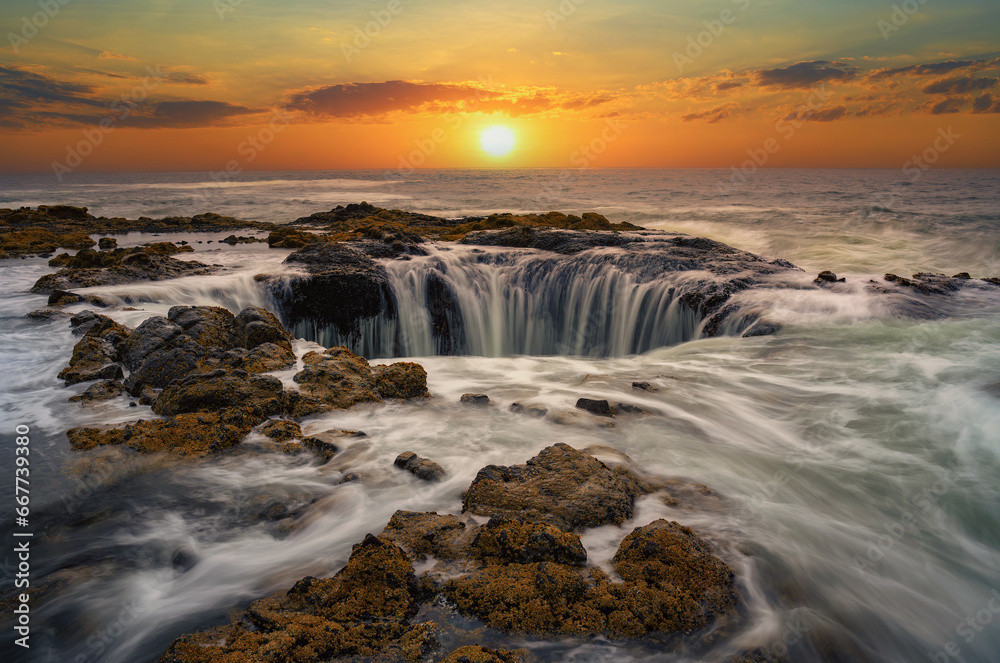 Water rushes into Thor's Well in Pacific Ocean at sunset in Oregon.