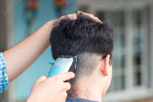 hand with hair clipper, cutting unrecognizable boy's hair