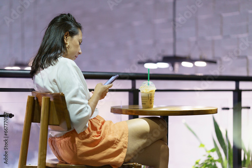 mujer con celular tomando bebida en un cafe 