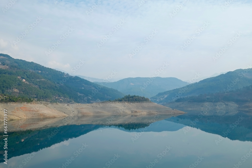 Beautiful view of mountain lake on a calm foggy day with gray cloudy skies. Copy space, background.