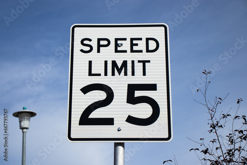 A white sign against a blue sky informing drivers that the speed limit is 25 miles per hour. 